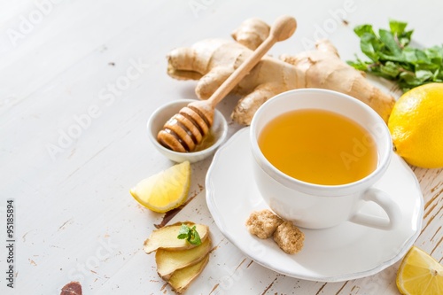 Ginger tea and ingredients on white wood background © anaumenko