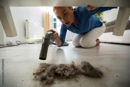 Surpriced housewife find dust under furniture photo
