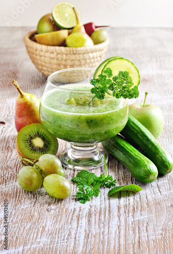 Refreshing green detox smoothie with ingredients on wooden background, selective focus
