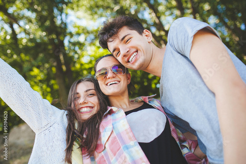 Happy teenage friends smiling outdoors on nature. Handsome young people having fun together and posing for camera. photo