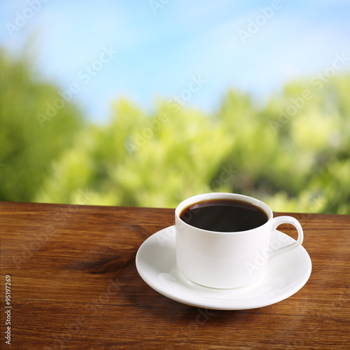 Cup of coffee on table on bright background