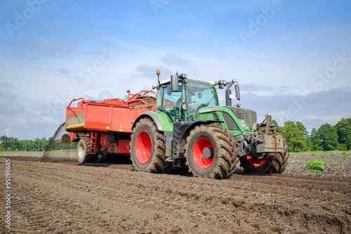 Traktor mit Kartoffelroder beim Kartoffeln ernten photo