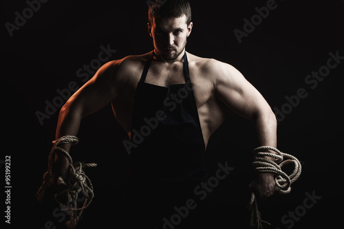 Muscular man in apron with rope