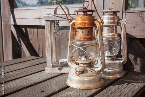 Rusted kerosene lamps stands on old wooden table © evannovostro