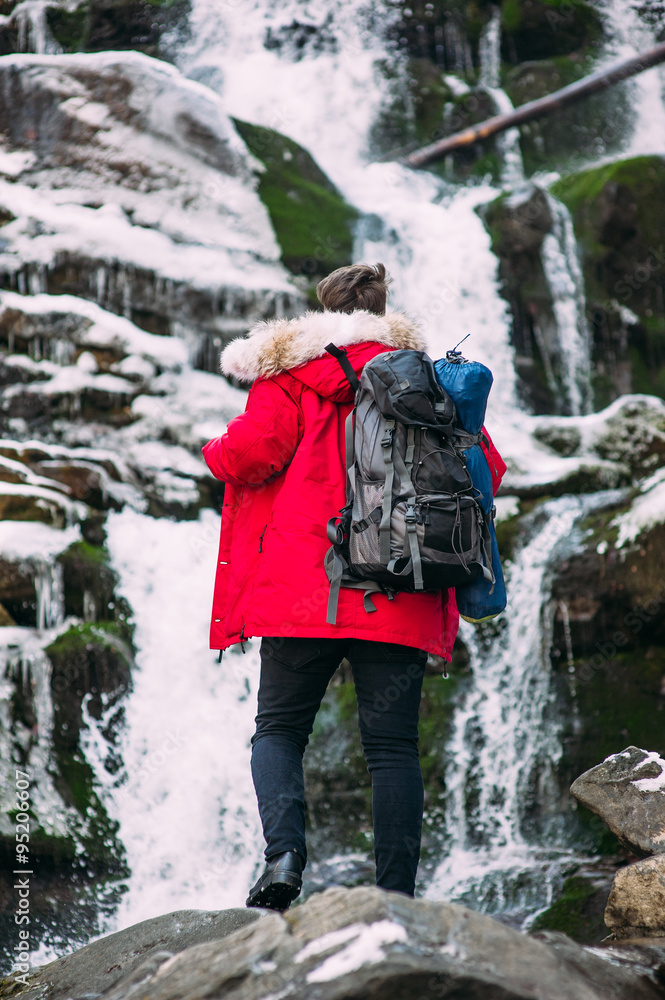 NICE guy model posing near the waterfall in winter mountains