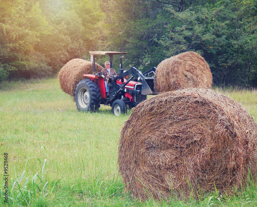 Adult man on tractor hauling hay at sunset