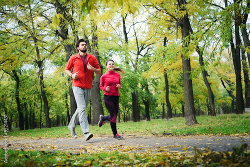 Fototapeta Naklejka Na Ścianę i Meble -  young caucasian couple running in autumn park, couple jogging together