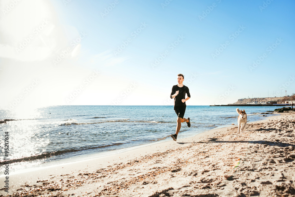 Running man. Male runner jogging with siberian husky dogs during the sunrise on beach
