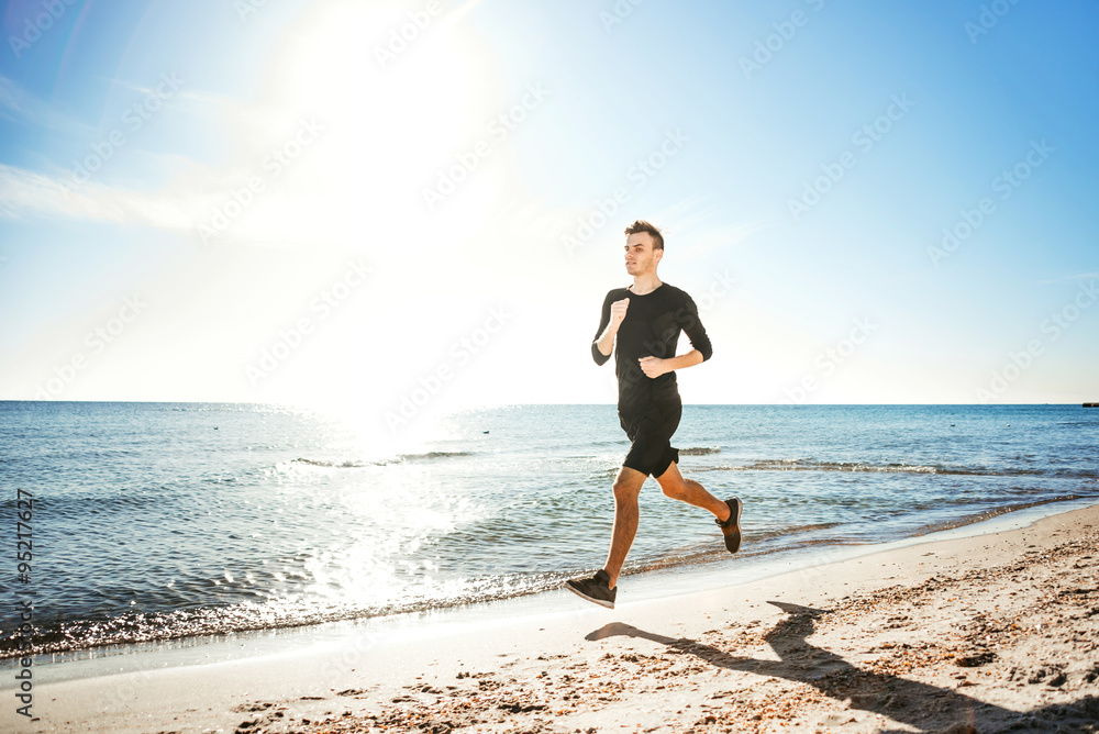 Running man. Male runner jogging during the sunrise on beach