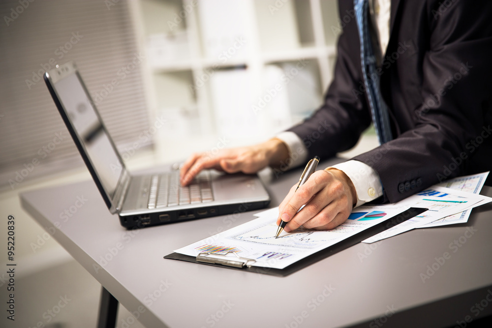Close up of male hands doing paperwork with pen and laptop. Close up of male hands doing paperwork with pen and laptop.