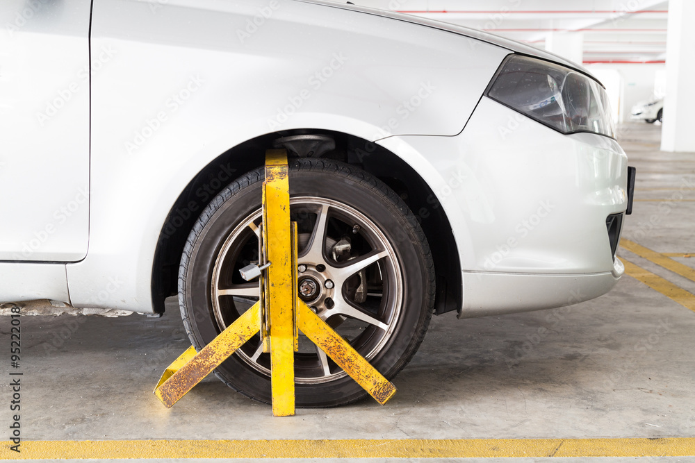 Car wheel clamped for illegal parking violation at car park foto de
