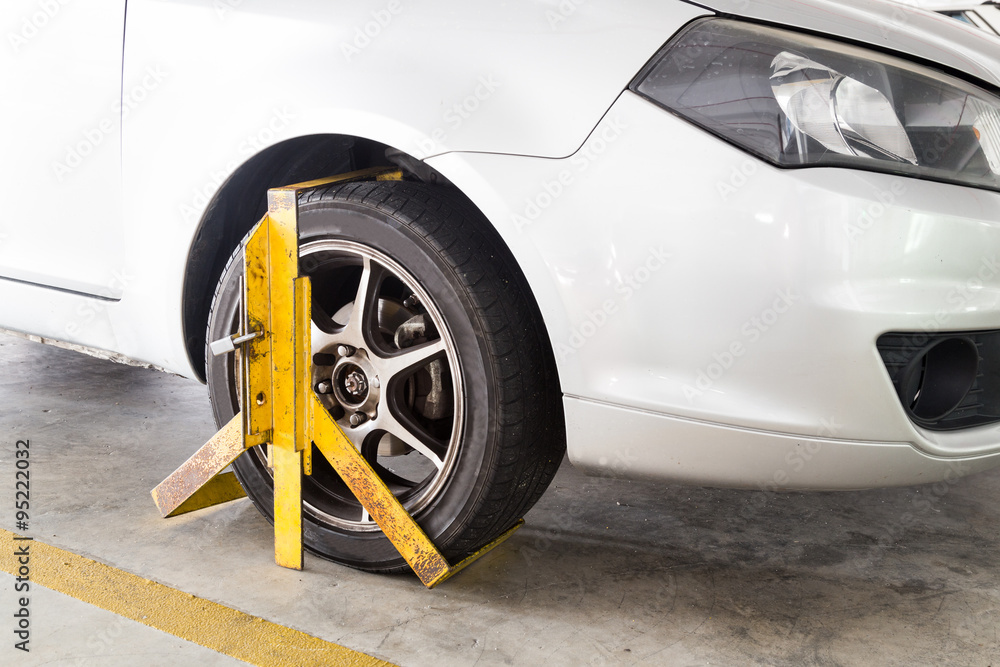 Obraz premium Car wheel clamped for illegal parking violation at car park