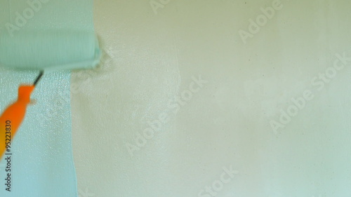 painting interior wall of home with paint roller