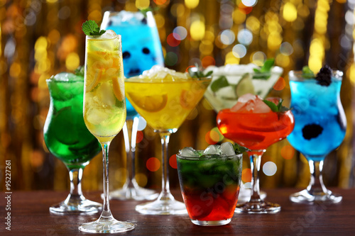 Glasses of cocktails with ice on blurred lights background
