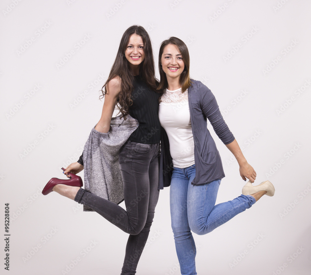 Fototapeta premium Two girls having fun in studio, white background