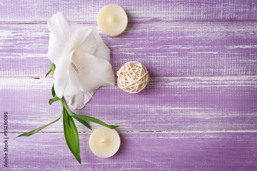 Spa composition of candles, oil and white flower on purple wooden background Spa composition of candles, oil and white flower on purple wooden background