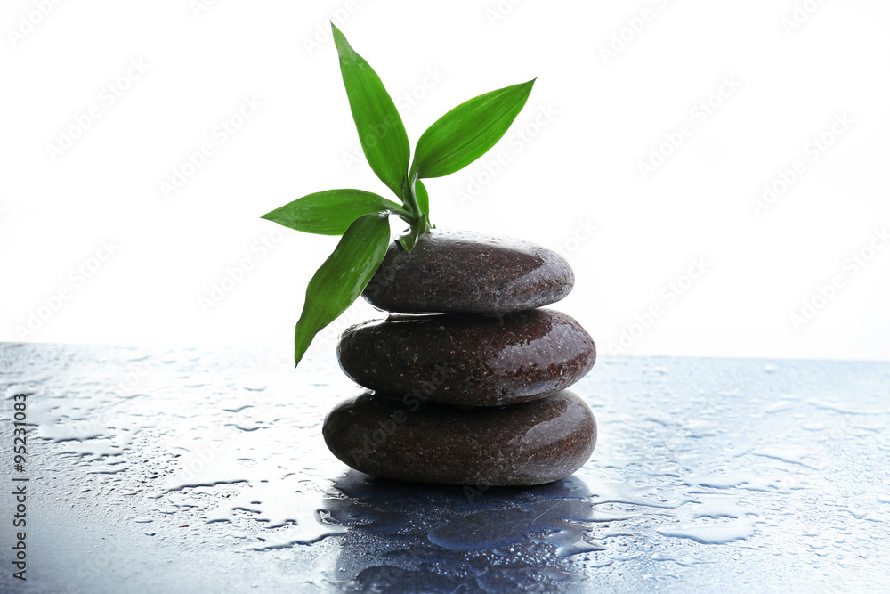 Naklejka premium Stack of stones and a green flower on white wet background. Spa relaxation concept