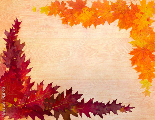 Frame of autumn leaves on a wooden surface