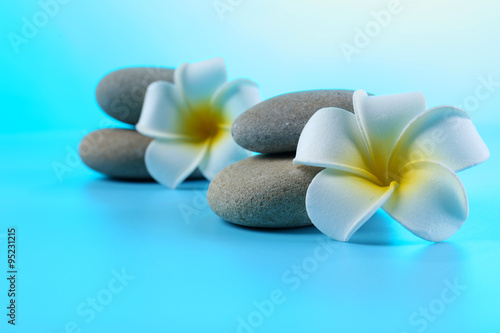 Spa stones and flowers on blue background
