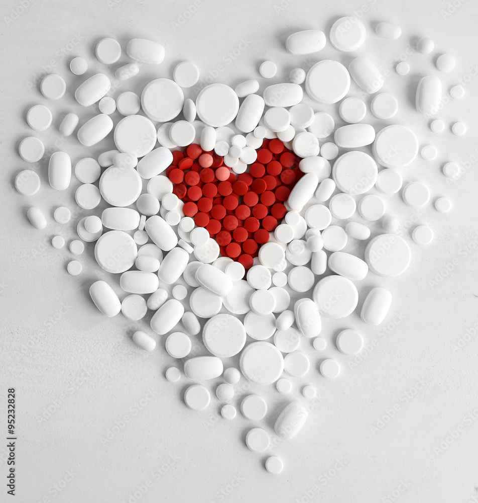 Heart of red pills on white pills background