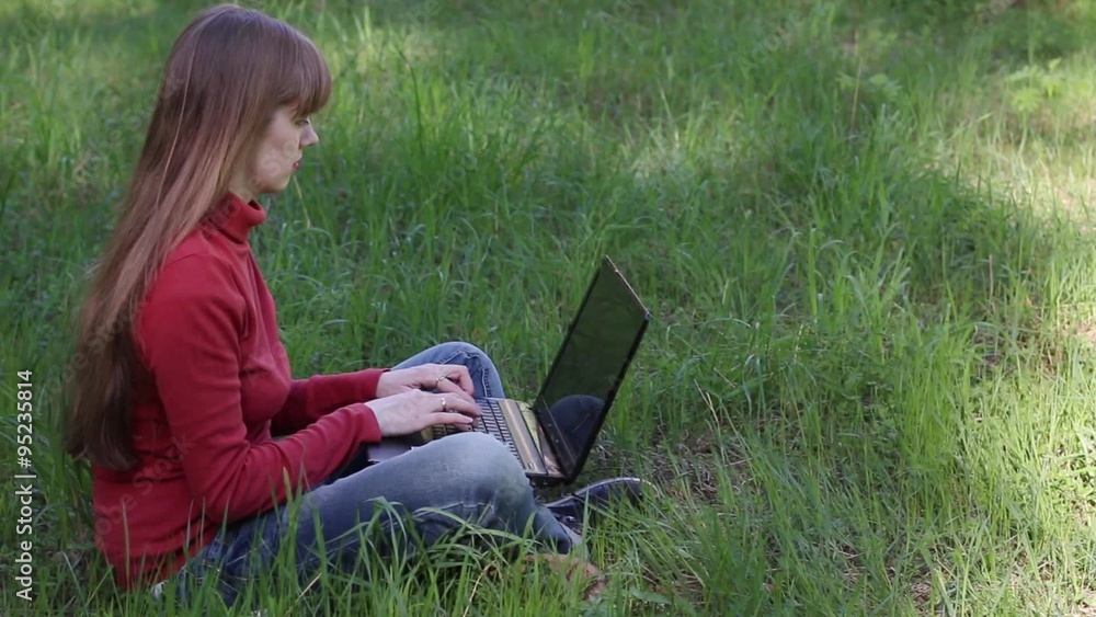Pretty woman typing on laptop and sitting on grass
Pretty woman typing on laptop and sitting on grass