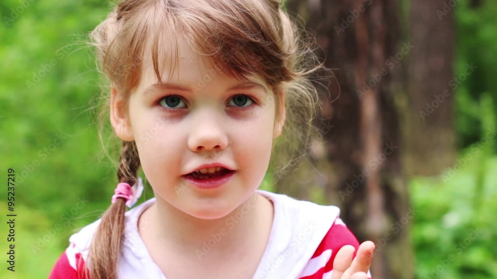 Little cute serious girl looks around in park. Close up view
Little cute serious girl looks around in park. Close up view