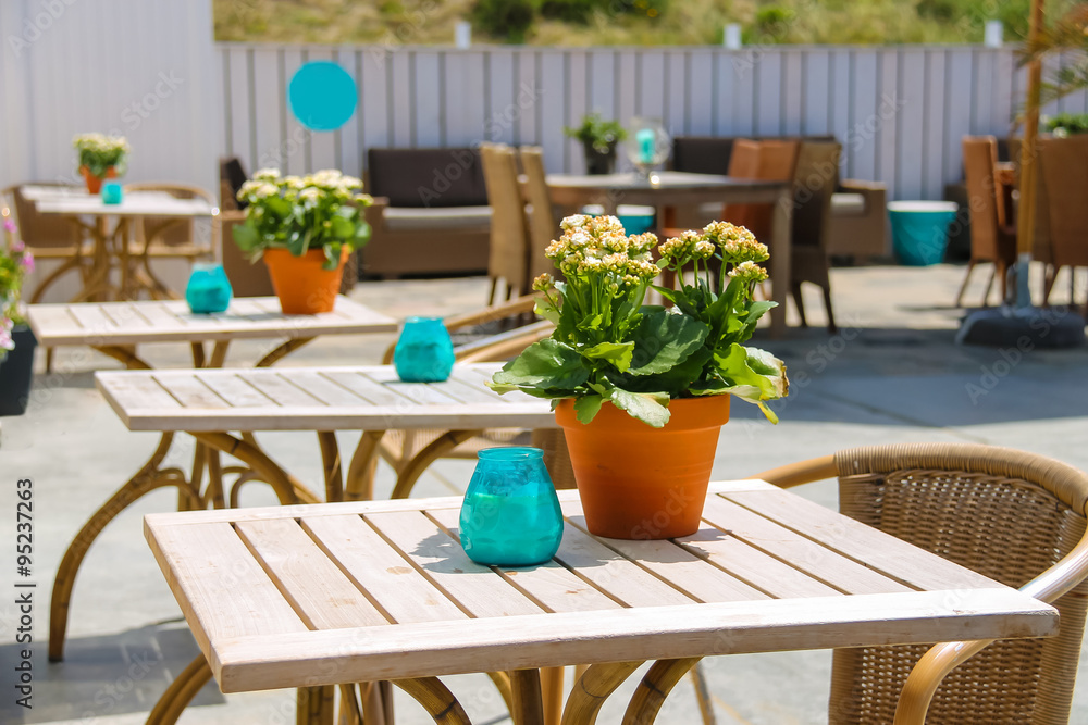 Obraz premium Flowers in pot and candles on the tables of beach cafe. Zandvoor