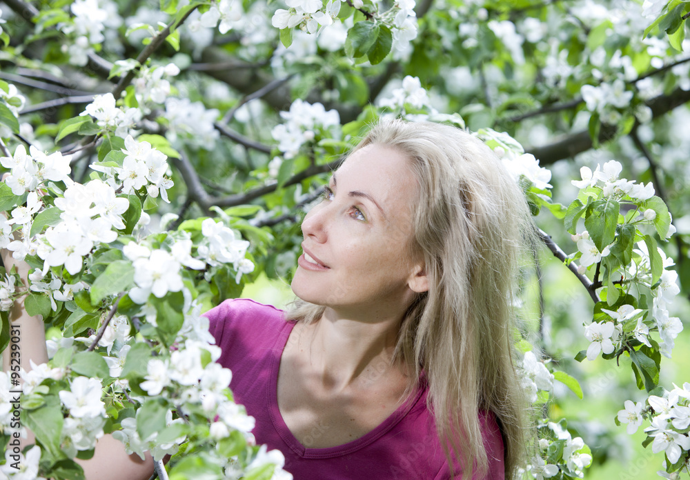 young attractive woman standing near the blossoming apple tree young attractive woman standing near the blossoming apple tree
