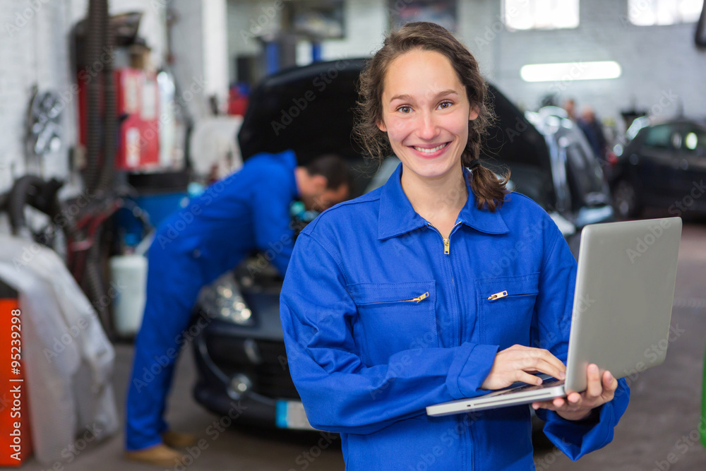 Young attractive woman mechanic working at the garage - obrazy, fototapety, plakaty 