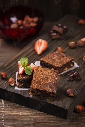 Homemade chocolate brownies with hazelnuts on grunge brown wooden background. Toned image. Selective focus