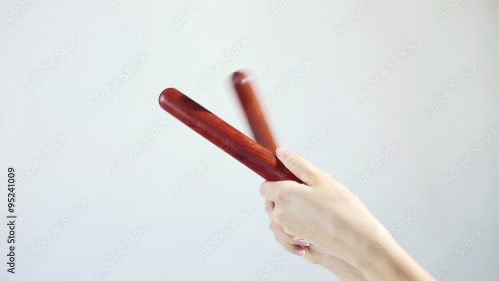 Hands playing on the musical sticks (percussion). Knock several times on a white background. Ethnic musical instruments. Hands playing on the musical sticks (percussion). Knock several times on a white background. Ethnic musical instruments.
