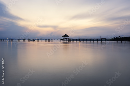 A wooden bridge leading to the sea on a beautiful sunset light.