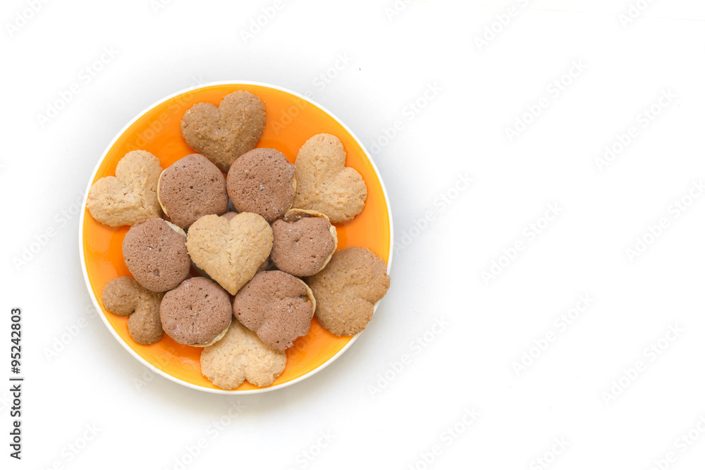 Chocolate cookies and butter cookies on orange dish on white background Chocolate cookies and butter cookies on orange dish on white background