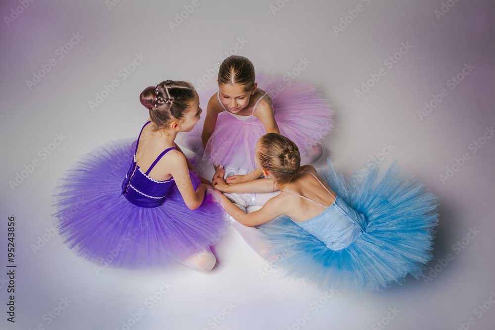 Fototapeta premium Three little ballet girls sitting in tutu and posing together