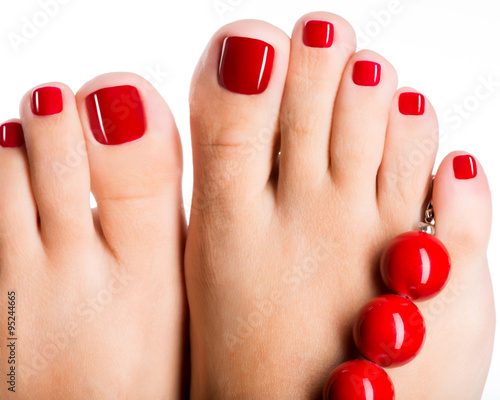 Closeup photo of a female feet with beautiful red pedicure