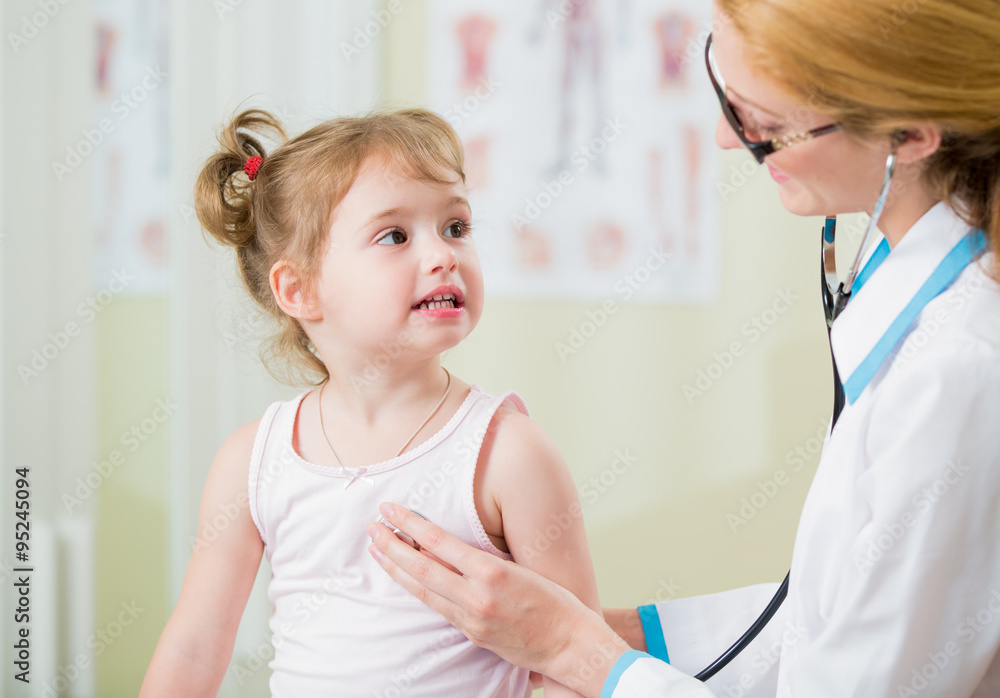 Pediatrician woman examining cute little girl with stethoscope. Kid happily smiling and looking at the doctor Pediatrician woman examining cute little girl with stethoscope. Kid happily smiling and looking at the doctor