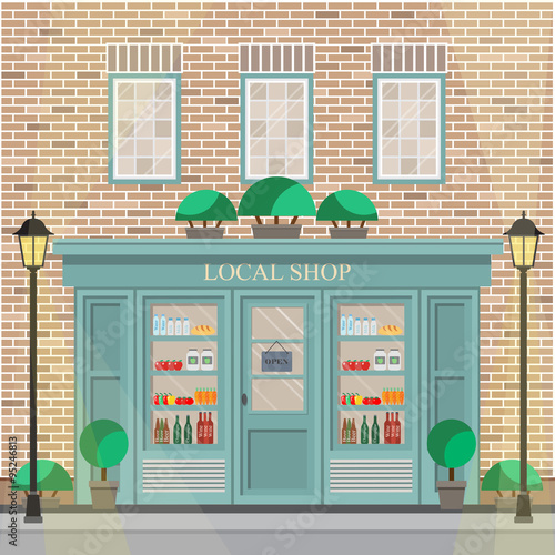 Facade of the building with local shop on the ground floor. The brick facade of the building with detailed windows.