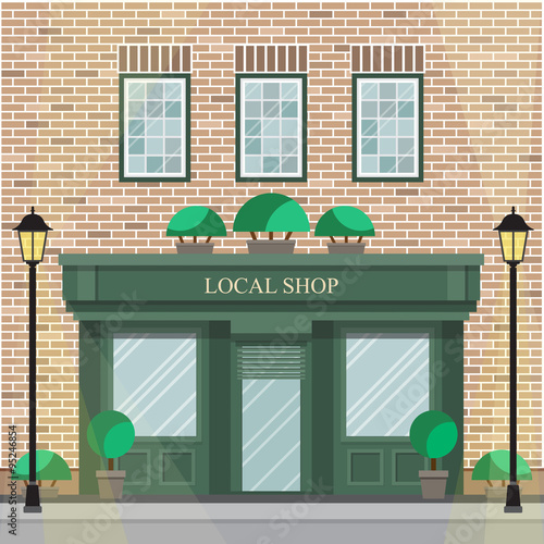 Facade of the building with local shop on the ground floor. The brick facade of the building with detailed windows.
