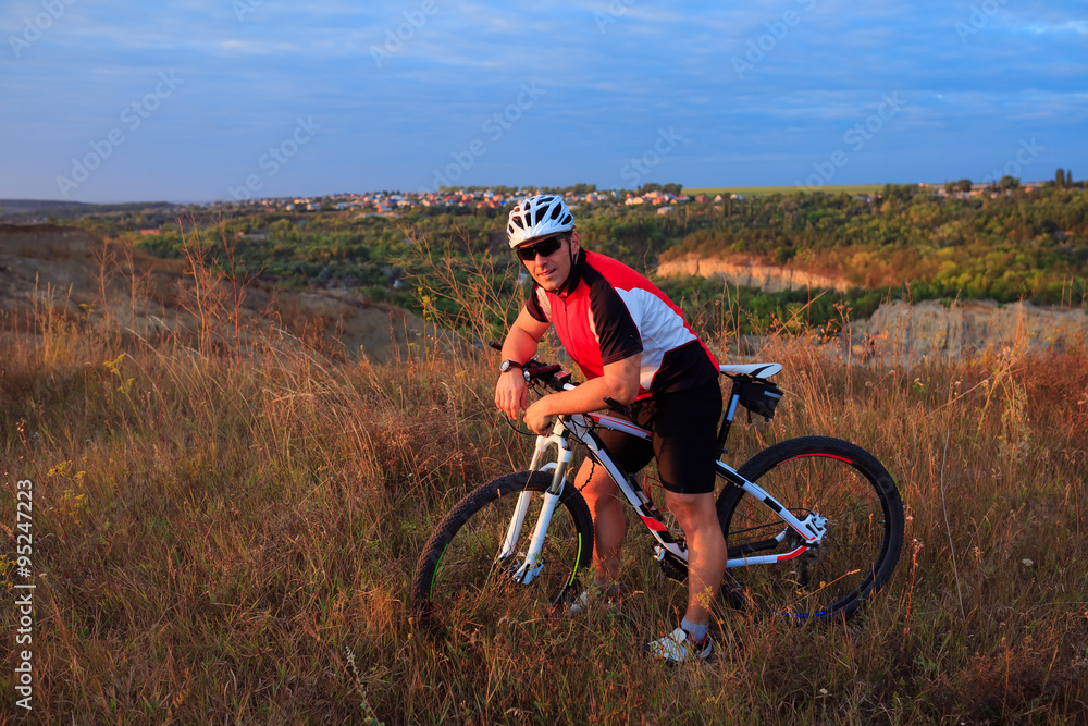 Obraz premium young adult cyclist riding mountain bike in the countryside