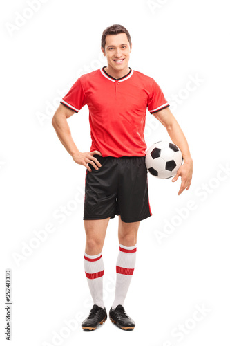 Young soccer player holding a ball and posing