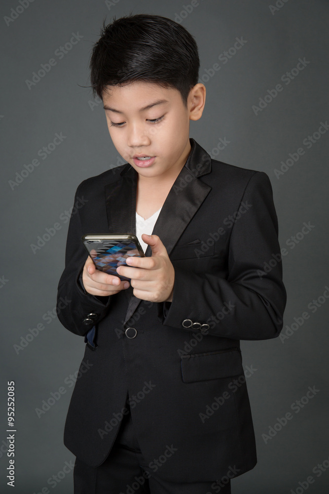 Happy asian child in black suit holding digital cell phone Happy asian child in black suit holding digital cell phone