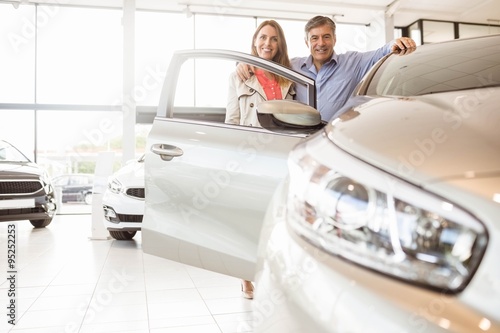 Murais de parede Smiling couple leaning on car