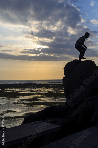 On a rock between sea and sky/A young Indonesian dancing on a rock between the sea and the sunset.