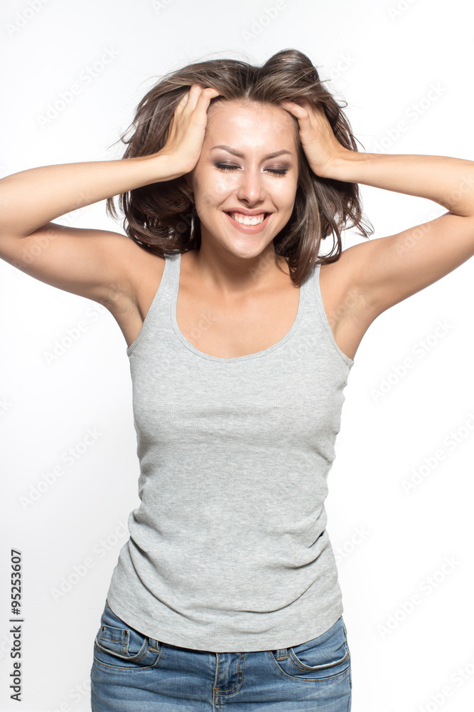 Awesome Caucasian attractive sexy female model with brunette hair is grimacing in studio, wearing grey sleeveless shirt and jeans, isolated on white background Awesome Caucasian attractive sexy female model with brunette hair is grimacing in studio, wearing grey sleeveless shirt and jeans, isolated on white background