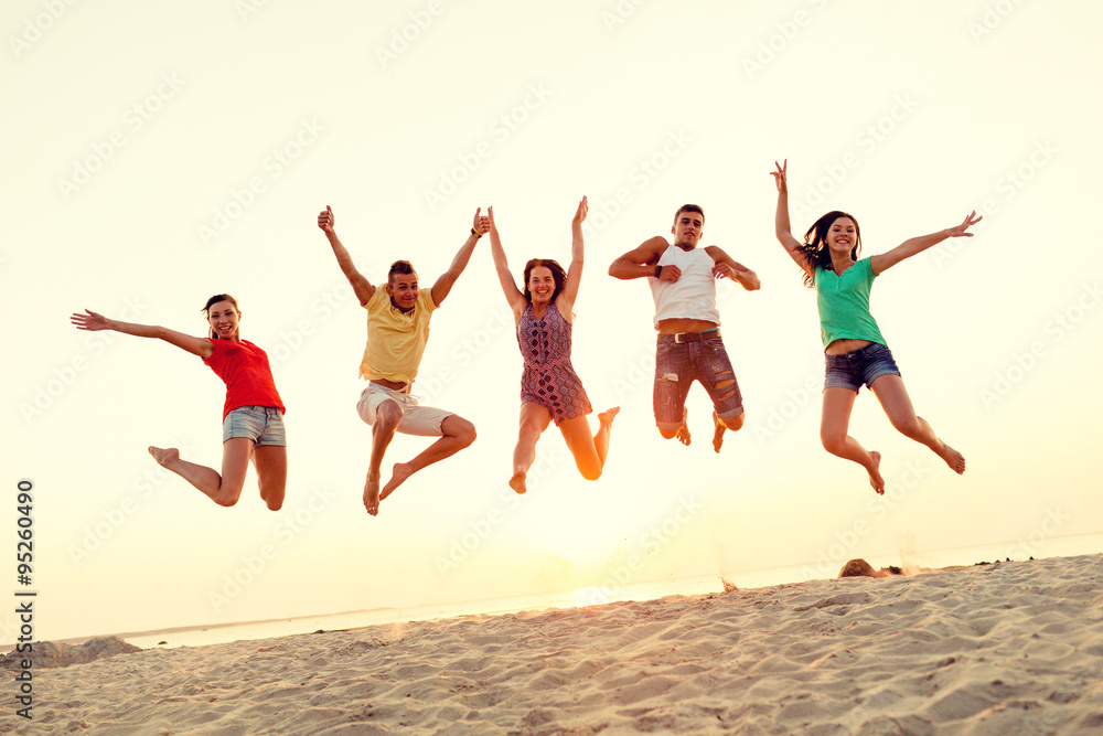 Fototapeta premium smiling friends dancing and jumping on beach