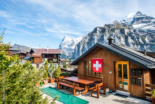 Wood chalet with Swiss flag in mountain village Murren at Jungfrau region, Switzerland.