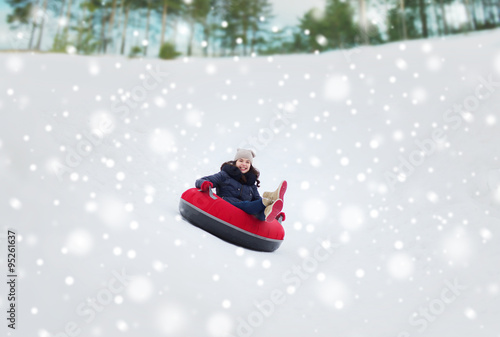 happy teenage girl sliding down on snow tube