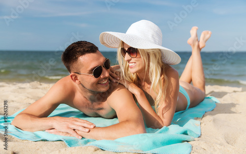 happy couple in swimwear lying on summer beach