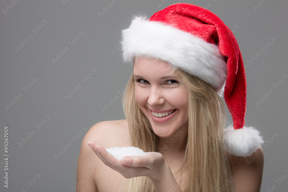 Hübsches Mädchen mit Nikolausmütze und Schnee in der Hand Hübsches Mädchen mit Nikolausmütze und Schnee in der Hand