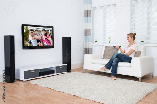 Woman Watching Television While Sitting On Sofa